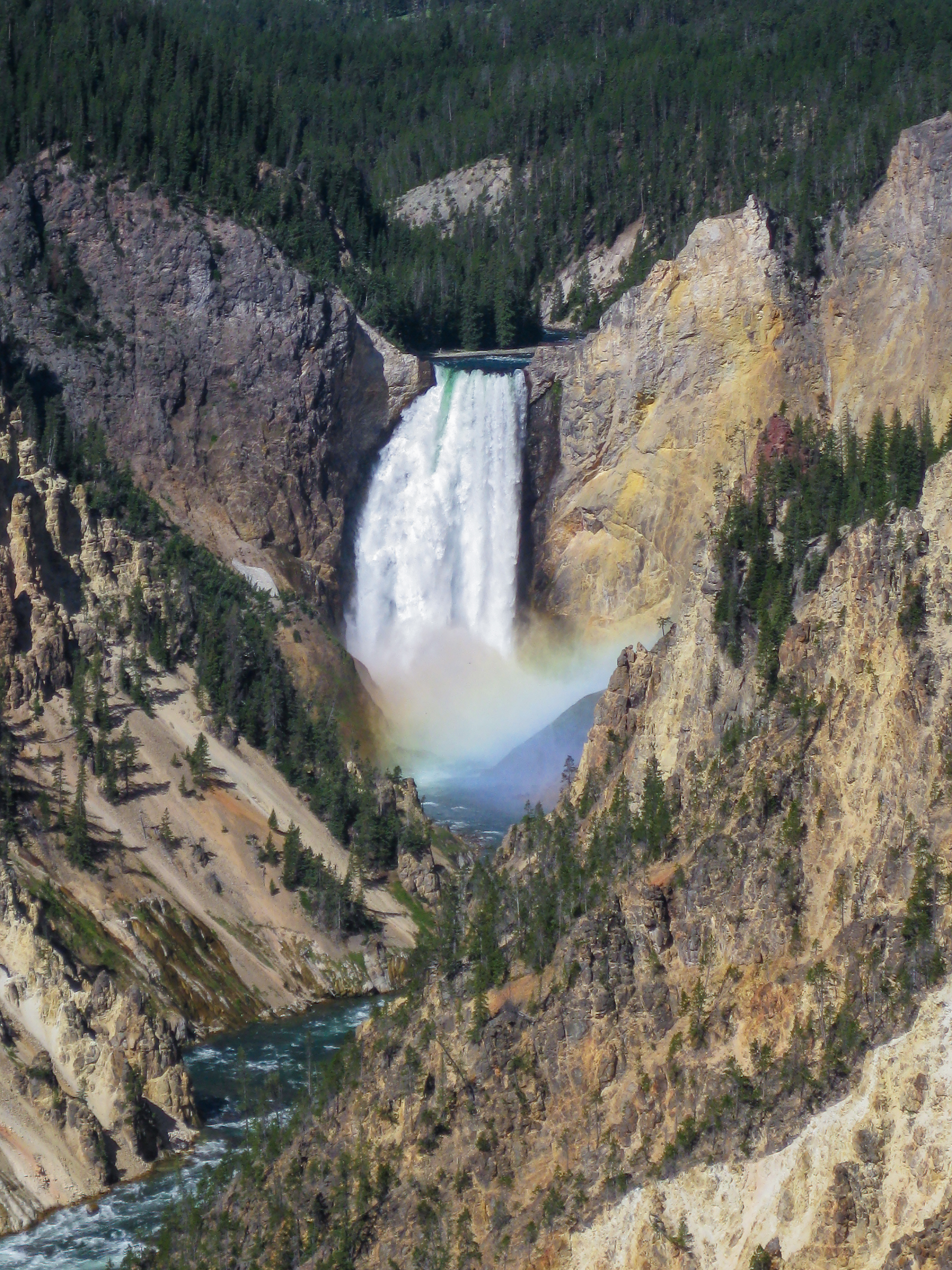 Waterfall dropping into a deep canyon with yellow and gray rock walls